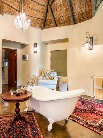 Hochwertig eingerichtetes Bad mit freistehender Badewanne und Teppichen in der Tintswalo Safari Lodge.