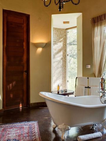 Luxuriöses Bad mit freistehender Badewanne und Blick auf die Natur in der Tintswalo Safari Lodge.