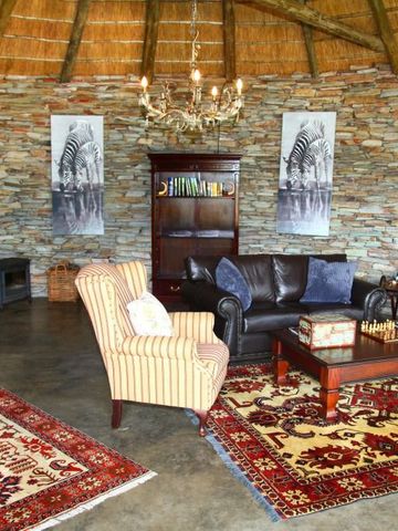 Elegante Lounge mit Steinwänden, Ledersofa, Kamin und Teppichen