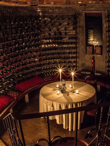 Atmosphärischer Weinkeller mit Kerzenlicht umgeben von Weinflaschen