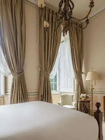 Helles Schlafzimmer mit hohen Fenstern und edlen Vorhängen