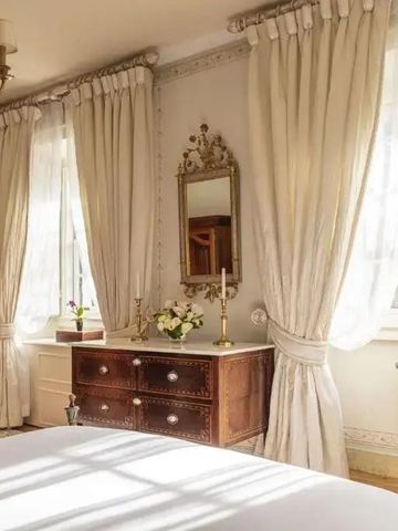 Helles Schlafzimmer mit Vorhängen und antikem Spiegel