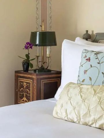 Bett mit gemusterten Kissen und dekorativem Nachttisch