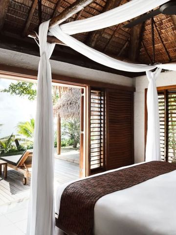 Luftiges Schlafzimmer mit Baldachinbett und Zugang zur Terrasse