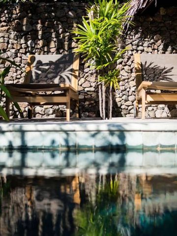 Sonnenliegen am Pool mit Natursteinmauer und Pflanzen