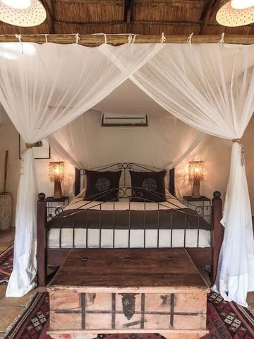Charmantes Schlafzimmer mit Baldachin und Holzakzenten in der Tongabezi Lodge