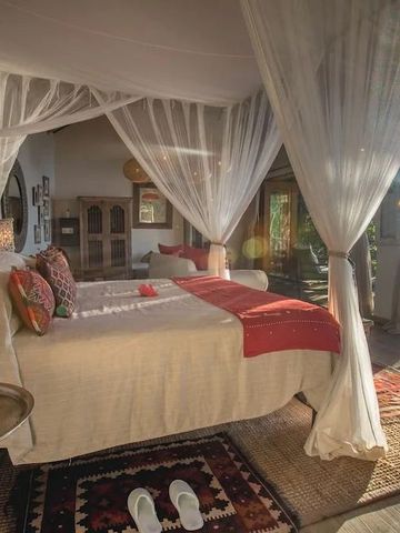 Geräumiges Zimmer mit Himmelbett und natürlichem Licht in der Tongabezi Lodge