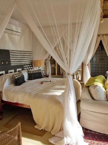 Elegantes Zimmer mit Baldachin und komfortabler Sitzecke in der Tongabezi Lodge