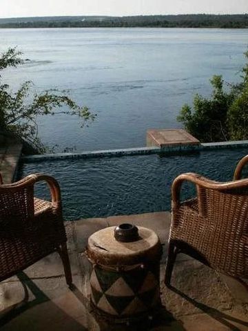 Zwei Korbstühle auf einer Terrasse mit Blick auf einen Fluss
