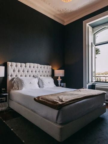 Schlafzimmer mit luxuriösem Doppelbett, dunklen Wänden und Balkonblick