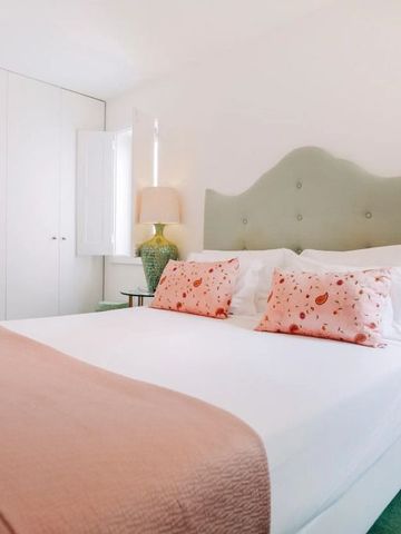 Helles Schlafzimmer mit großem Bett, pastelligen Farben und Tageslicht