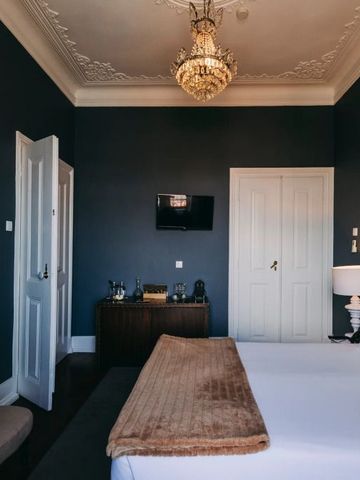 Elegantes Schlafzimmer mit Stuckdecke, Kronleuchter und schickem Dekor