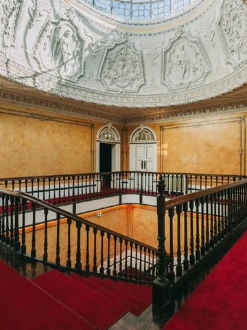 Prächtige Kuppeldecke mit reich verziertem Geländer und rotem Teppich im Torel Palace Porto