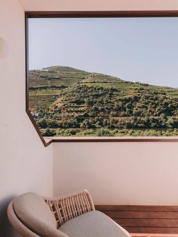 Balkonbereich mit gemütlichem Rattan-Sessel und Blick auf die Weinberge