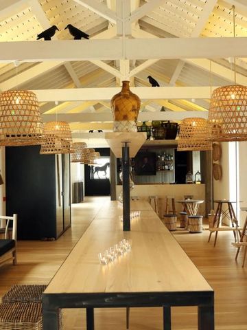 Einladender Raum mit Holztischen und Korblampen in heller, offener Konstruktion