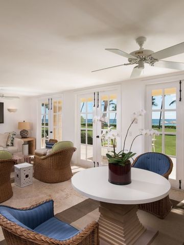 Wohnbereich mit Rattanmöbeln, großem Fenster mit Meerblick