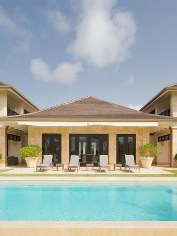 Luxuriöse Villa mit Pool und Sonnenliegen vor einem blauen Himmel