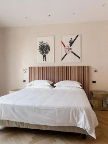 Minimalistisch gestaltetes Zimmer mit Kunstwerken über dem Bett