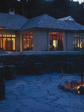 Beleuchtete Lodge in der Dämmerung mit Außenfeuerstelle