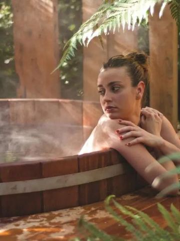 Entspannte Person in einem dampfenden heißen Outdoor-Whirlpool mit Pflanzenumgebung