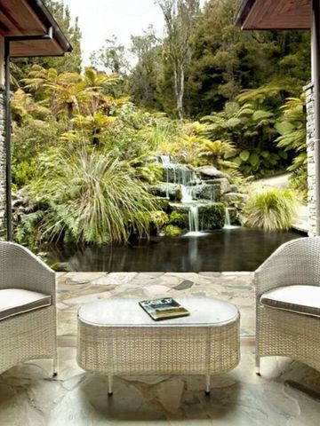 Idyllischer Innenhof mit Sitzmöbeln und Blick auf Teich und Wasserfall