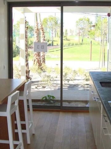 Moderne Küche mit Blick auf grüne Gartenlandschaft durch große Fensterfront.