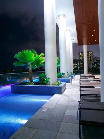 Nachts beleuchtete Poolterrasse mit Liegestühlen und urbaner Aussicht