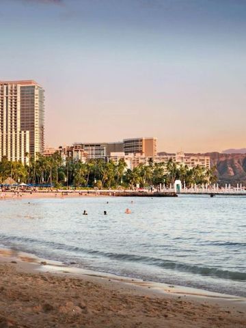 Strandszene mit hellem Sand und Hotelhintergrund bei Sonnenuntergang