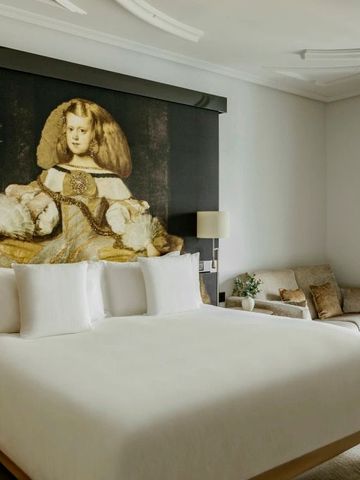 Elegantes Hotelzimmer mit großem Gemälde im Hintergrund und einem gemütlichen Sofa