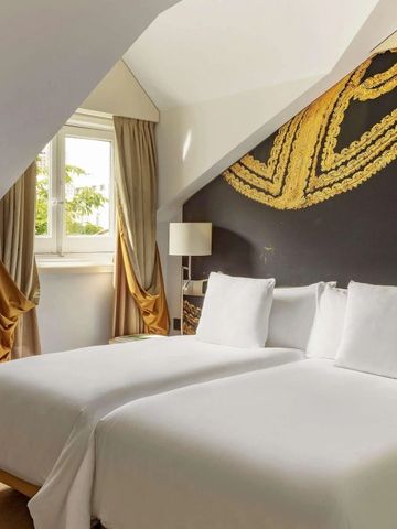 Charmantes Dachzimmer mit weißem Bett und kunstvollem Wandgemälde