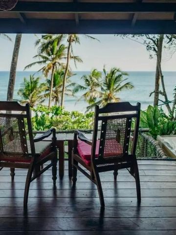 Zwei Stühle auf Terrasse mit Meerblick und Palmen im Hintergrund