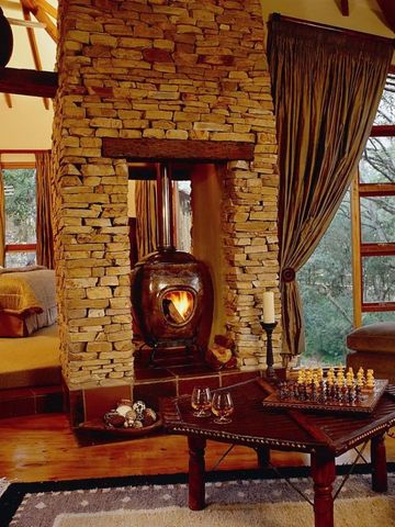 Gemütliches Zimmer mit Kamin aus Stein im Tsala Treetop Lodge mit Waldblick