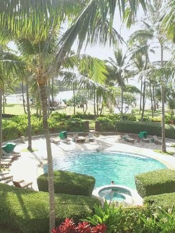 Poolbereich mit Palmen und Garten im Hintergrund.