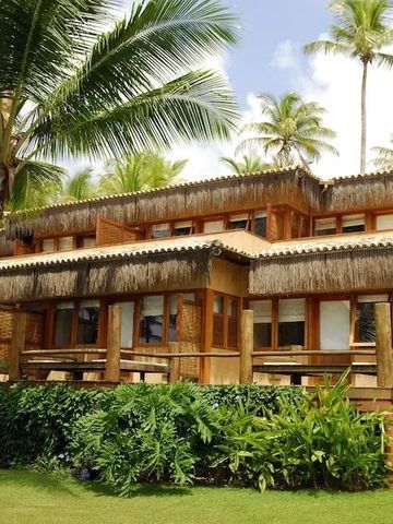 Hotelgebäude mit Strohdach und tropischem Garten
