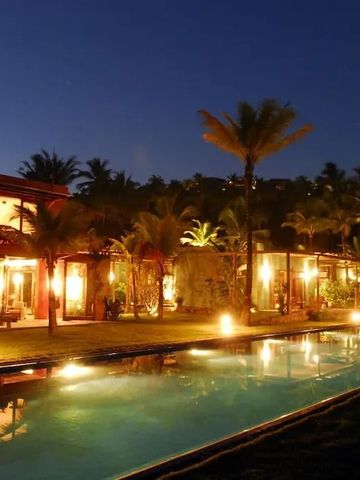 Beleuchteter Pool und Hotelgebäude bei Nacht umgeben von Palmen