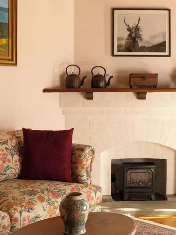 Eleganter Kaminbereich mit dekorativer Teekannen-Ansammlung und floraler Couch.