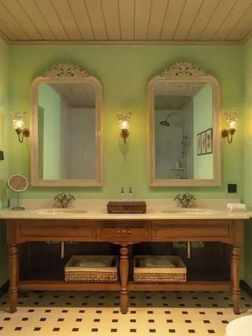 Badezimmer mit grünen Wänden und großen Spiegeln über dem Waschtisch.
