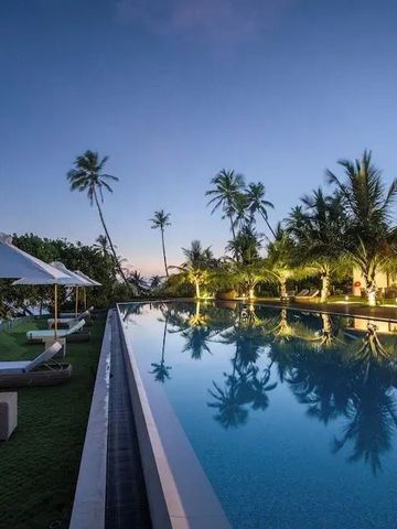 Infinity-Pool bei Sonnenuntergang umgeben von Palmen