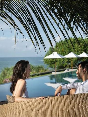 Paar entspannt am Infinity-Pool mit Blick auf das Meer