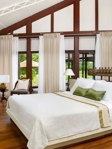 Moderne Suite mit großem Bett und Fenster mit Vorhängen