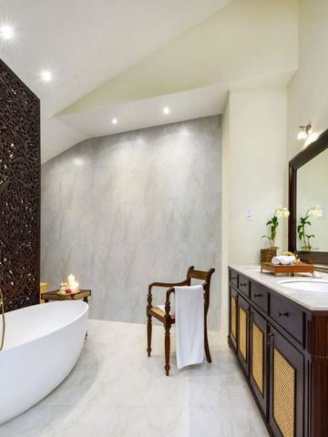 Luxuriöses Badezimmer mit freistehender Wanne und aufwendig geschnitztem Holzelement