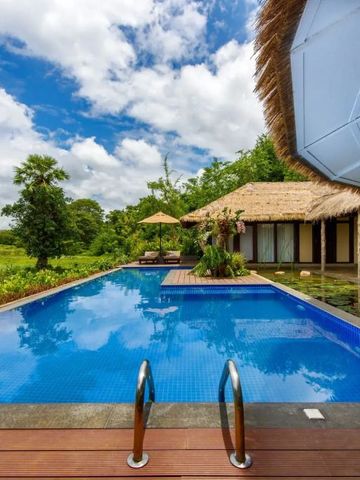 Infinity-Pool mit Sonnenliegen und strohgedecktem Pavillon unter blauem Himmel