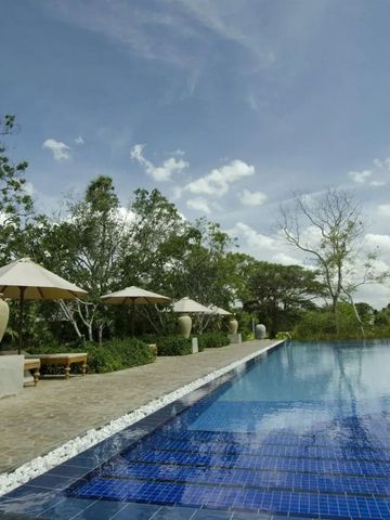 Großer Pool mit Sonnenschirmen und üppiger Vegetation umgeben
