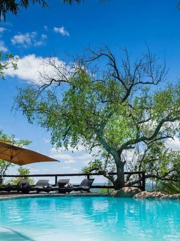 Pool umgeben von Natur mit Liegestühlen unter Sonnenschirmen