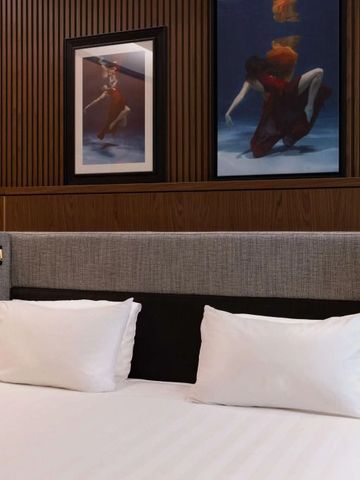 Helles Hotelzimmer mit Doppelbett und eleganten Kunstwerken an der Wand