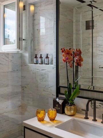 Helles Badezimmer mit schönen Marmordetails und frischen Pflanzen