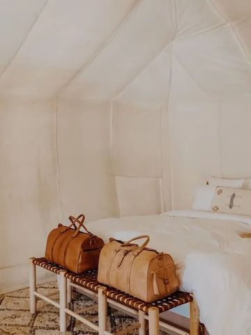 Lichtdurchflutetes Zeltzimmer mit großer Matratze und Ledertaschen.