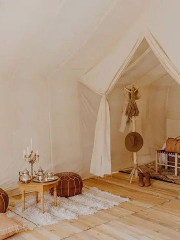 Zeltbereich mit Poufs und kleiner Teetisch, dezente Inneneinrichtung.