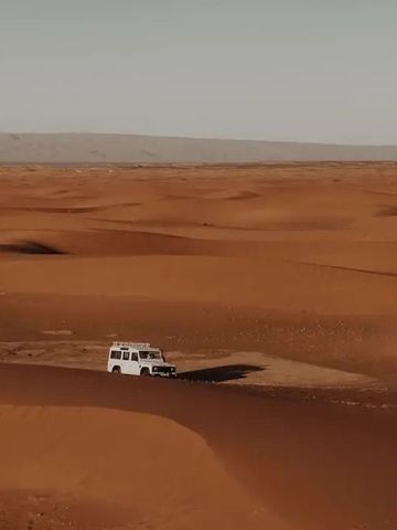Weite Sanddünenlandschaft mit Fahrzeug in der Wüste