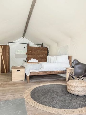 Gemütliches Zeltinterieur mit Holzmöbeln und Kaminofen